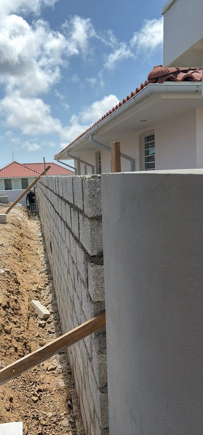 Long retaining wall along a house, during construction